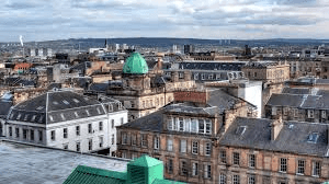 Glasgow city rooftops and historic buildings with a copper dome under cloudy skies
